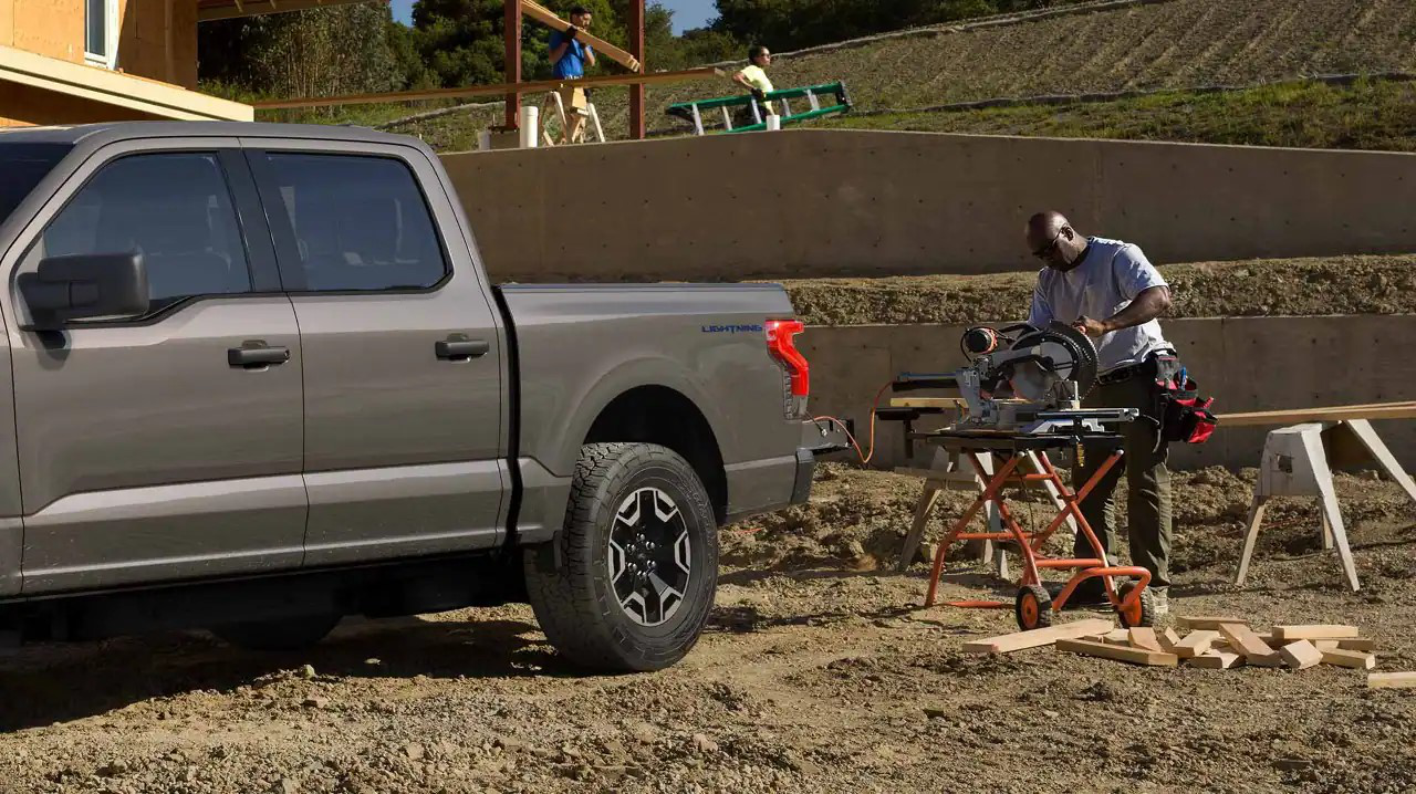  A worker using the Ford F-150 Lightning Pro's Pro Power Onboard to power tools.