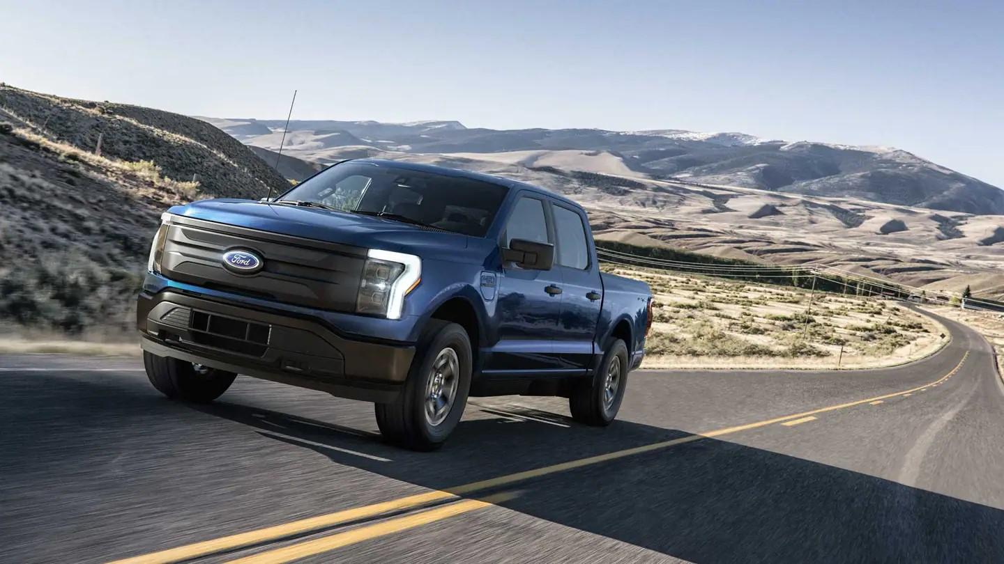 Ford F-150 Lightning Pro driving on the road through a rural area.