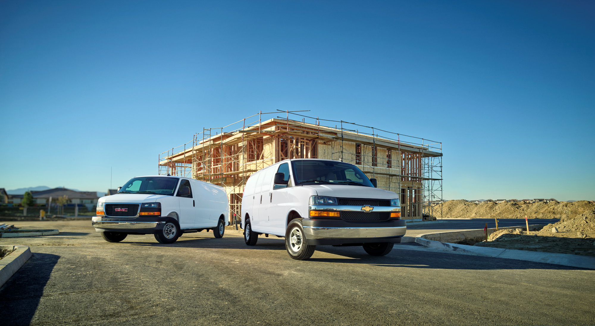 Two white cargo vans on a construction site