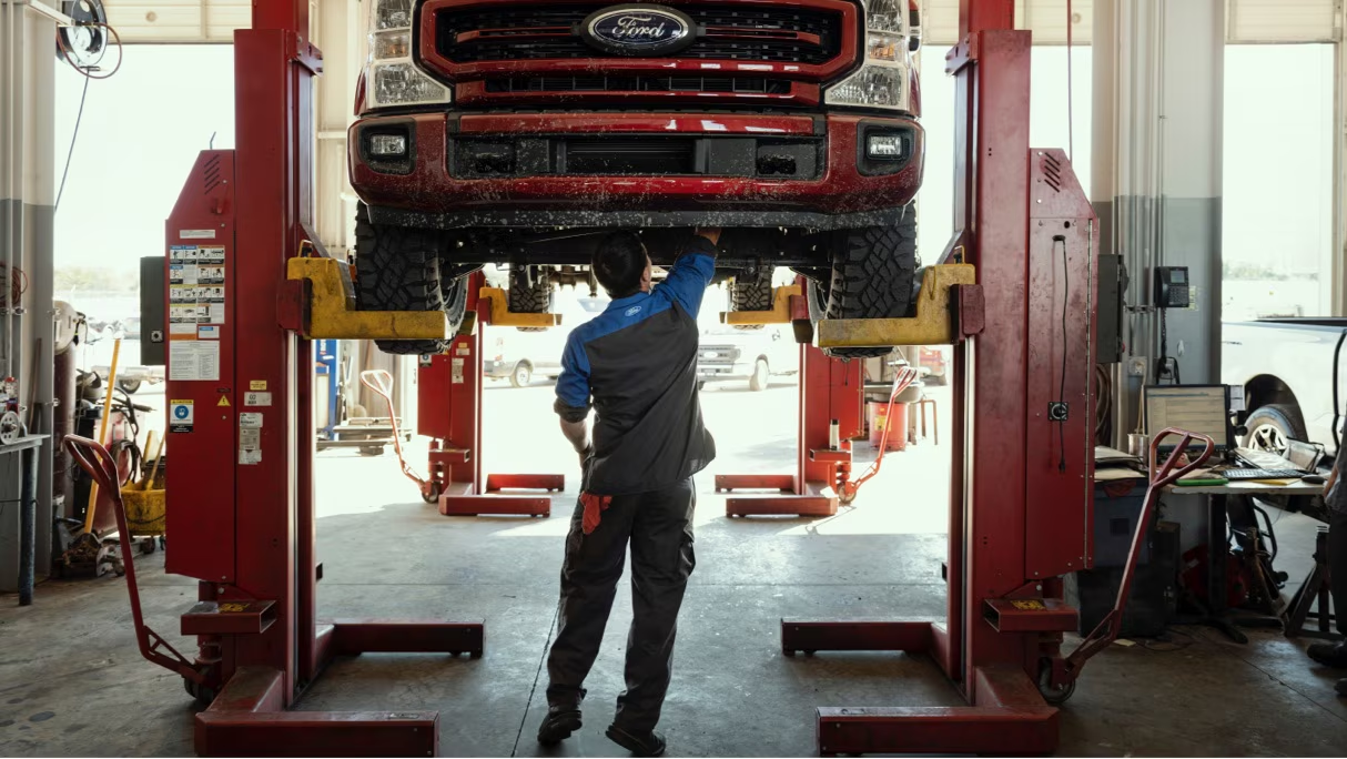 Truck on lift with technician working on it